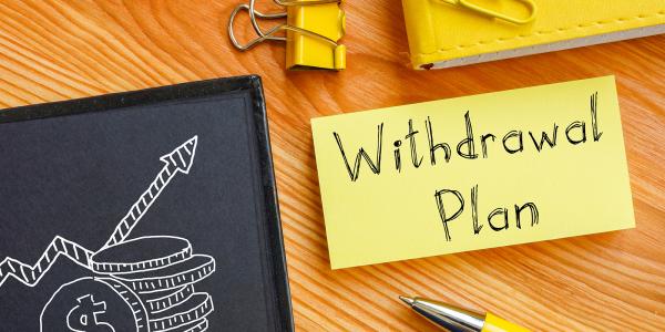 a post-it note on a desk with the words 'WITHDRAWAL PLAN' written on it.