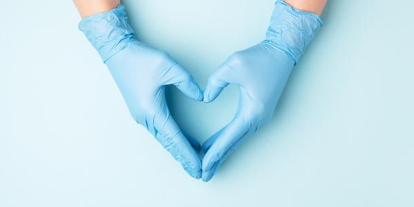 care workers hands wearing blue gloves and holding their hands to shape a heart