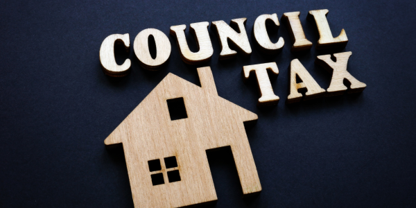 a house and the words 'council tax' carved from wood against a navy blue background a house and the words 'council tax' carved from wood against a navy blue background