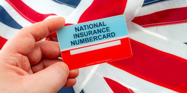 a person holding a 'national insurance numbercard' with a flag of The United Kingdom in the background