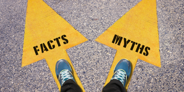 a person stood with one foot each on a yellow arrow one pointing left with the word 'FACTS' written on it, the other pointing right with the word 'MYTHS' written on it 