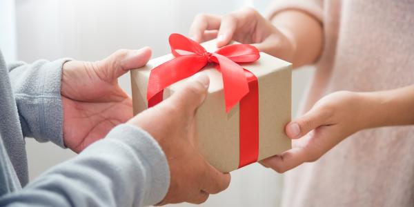 a person handing a gift to someone else. a person handing a gift to someone else.