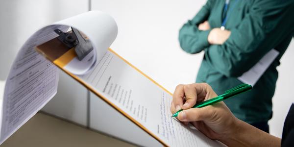 a person taking notes on a clipboard. 