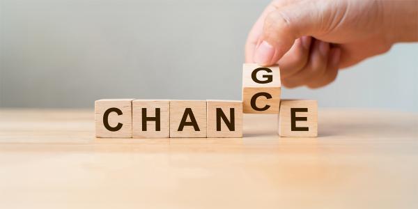 wooden blocks spelling out the word 'CHANGE' the letter G is tilted by a person to make the word read as 'CHANCE'