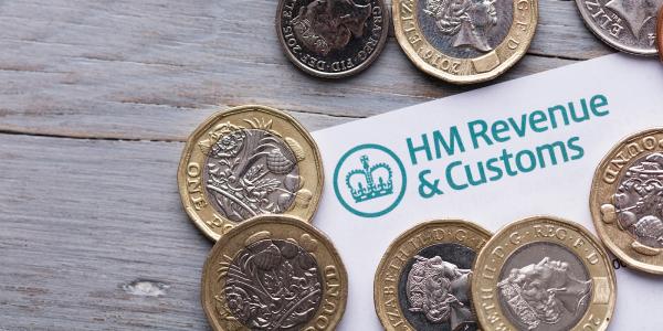 a letter from HMRC showing the logo in the top left corner, pound coins are scattered on top of the letter. 