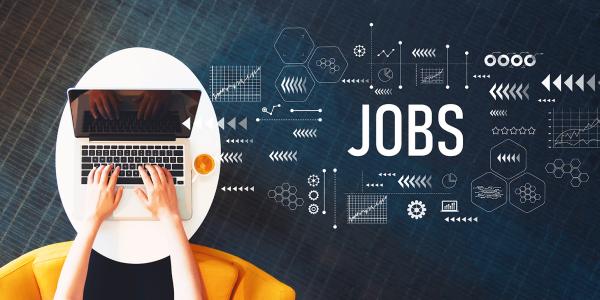 person sat in a yellow chair at a table with their laptop. the word 'JOBS' can be seen to the right hand side along with lots of various icons. person sat in a yellow chair at a table with their laptop. the word 'JOBS' can be seen to the right hand side along with lots of various icons.