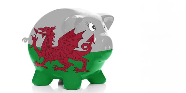 a ceramic piggy bank on a white background decorated with the Welsh flag