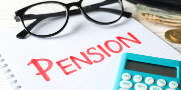 a pad of paper with the word 'PENSION' written on it with red ink, a calculator and a pair of glasses. a pad of paper with the word 'PENSION' written on it with red ink, a calculator and a pair of glasses.