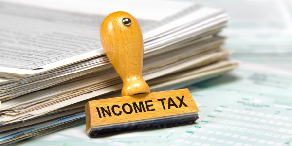 a stack of paperwork with a stamp leaning up against it, the stamp ready 'INCOME TAX' a stack of paperwork with a stamp leaning up against it, the stamp ready 'INCOME TAX'