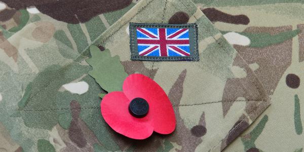 Close up of a British army uniform, a poppy and a UK flag patch