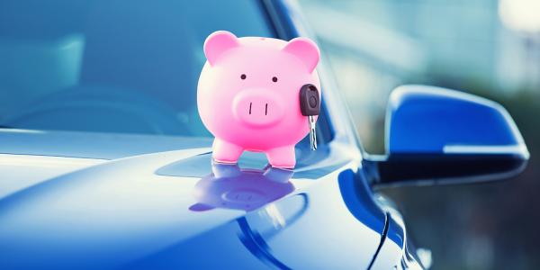 a blue car with a pink piggy bank and car key on the bonnet