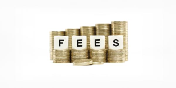 4 piles of coins each with a small building block on top, spelling out the word 'FEES'. behind these 4 piles are a further 5 piles of coins. 4 piles of coins each with a small building block on top, spelling out the word 'FEES'. behind these 4 piles are a further 5 piles of coins.