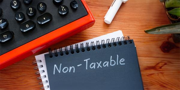 a black pad of paper on a desk with the word 'NON-TAXABLE' written in white pen.