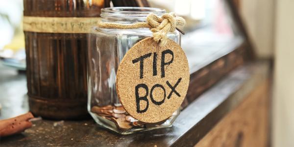a glass jar with a label reading 'TIP BOX' sat on a counter top a glass jar with a label reading 'TIP BOX' sat on a counter top