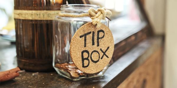 a glass jar with a label reading 'TIP BOX' sat on a counter top