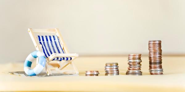 a beach chair, swim ring and stacks of coins on a makeshift beach. 