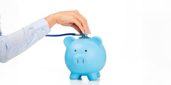 a person holding a stethoscope to a blue piggy bank. 