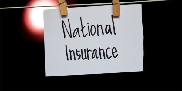 A wire with 2 wooden pegs holding a white sign with back text that reads 'NATIONAL INSURANCE' there is a black background with a singular circle of light to the left of the sign.