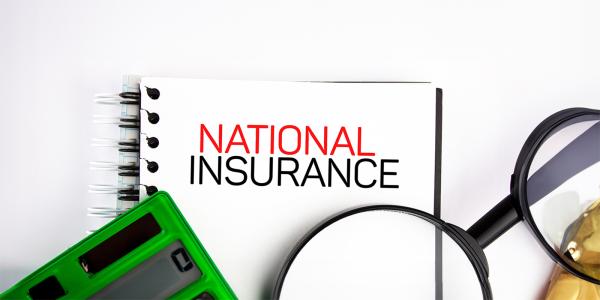a wire bound notebook with the words 'NATIONAL INSURANCE' typed on the front in back and red text, a green calculator and a magnifying glass a wire bound notebook with the words 'NATIONAL INSURANCE' typed on the front in back and red text, a green calculator and a magnifying glass