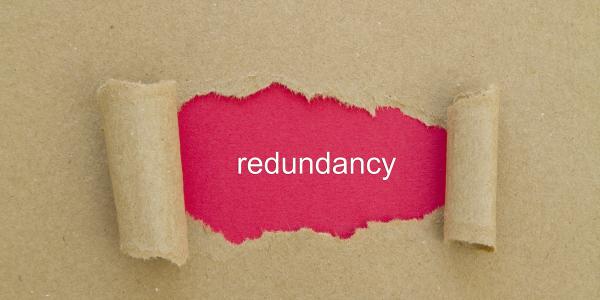 a sheet of brown paper ripped in the middle to reveal red paper with the word 'REDUNDANCY' in white ink. 