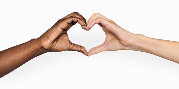 2 people holding hands out to one another, where their hands touch they are making the shape of a heart