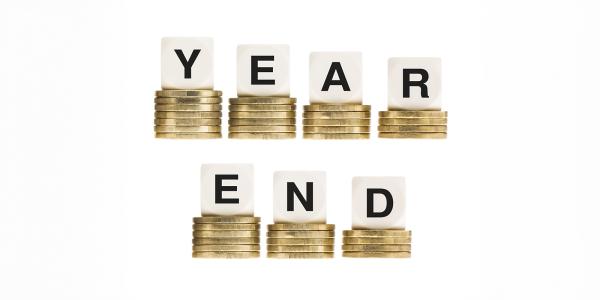 7 piles of coins, each with a dice on top, instead of showing dots to represent numbers, they show letters spelling out 'YEAR END' 