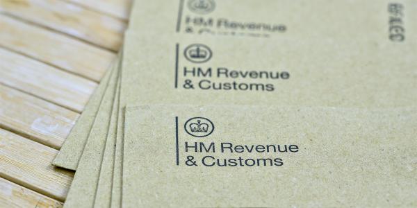 a pile of brown envelopes on a wooden table, each envelope has 'HM REVENUE & CUSTOMS' printed in the top left corner along with the HMRC logo. a pile of brown envelopes on a wooden table, each envelope has 'HM REVENUE & CUSTOMS' printed in the top left corner along with the HMRC logo.