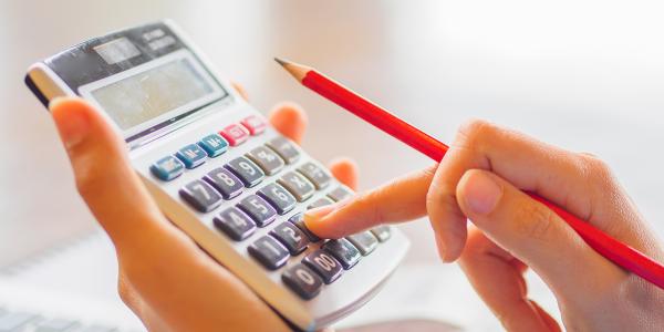 person typing on a calculator whilst holding a pencil person typing on a calculator whilst holding a pencil