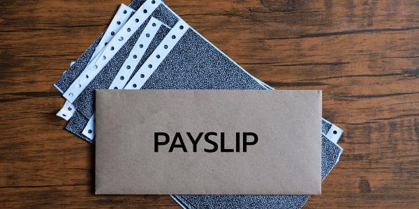 a stack of paper with an envelope on top, typed on the envelope is the word 'PAYSLIP' 