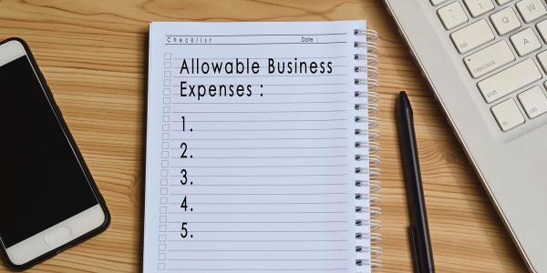 a desk with a pad of writing paper, written on the paper are the words ' ALLOWABLE BUSINESS EXPENSES' 