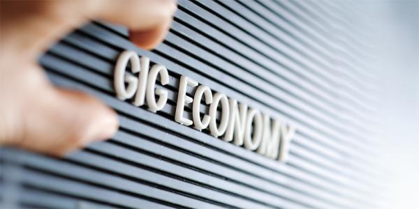 the words 'GIG ECONOMY' spelt out in white letters on a dark coloured board. the words 'GIG ECONOMY' spelt out in white letters on a dark coloured board.