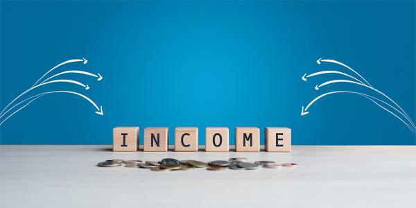 Wooden blocks spelling out the word 'INCOME' against a blue background, white arrows are pointing towards the word. Wooden blocks spelling out the word 'INCOME' against a blue background, white arrows are pointing towards the word.