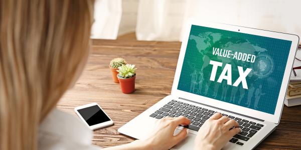 a person at a laptop, the screen shows the words 'VALUE ADDED TAX' a person at a laptop, the screen shows the words 'VALUE ADDED TAX'