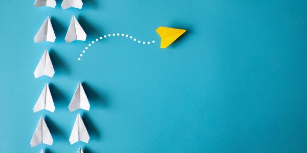 white paper aeroplanes pointing upwards, with one yellow paper aeroplane veering off to the right and leaving the rest. white paper aeroplanes pointing upwards, with one yellow paper aeroplane veering off to the right and leaving the rest.