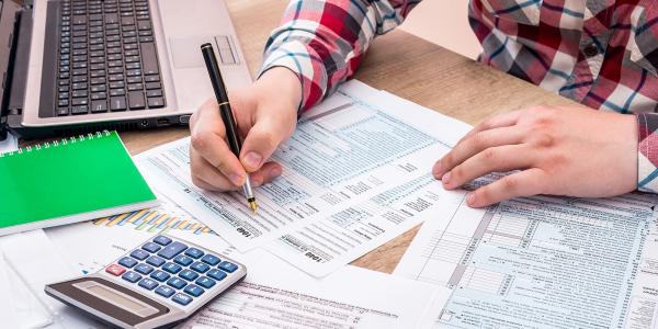 a person sat at a desk surrounded by various stationary, filling out a form.