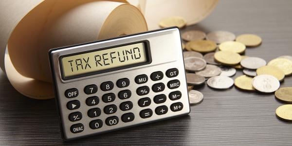 a calculator displaying the words 'TAX REFUND' coins scattered in the background a calculator displaying the words 'TAX REFUND' coins scattered in the background