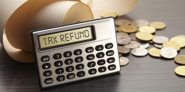 a calculator displaying the words 'TAX REFUND' coins scattered in the background