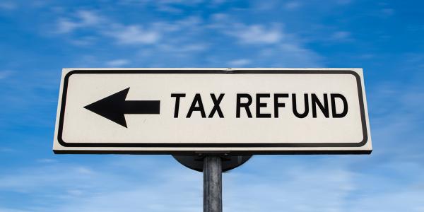 a blue sky background with a street sign saying 'TAX REFUND' a blue sky background with a street sign saying 'TAX REFUND'