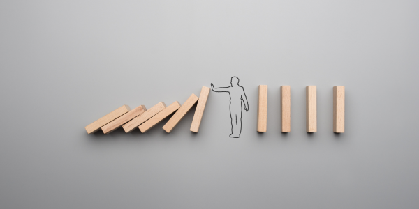 wooden blocks falling on one another then an outline of a person with their hand held out stopping the blocks from falling further