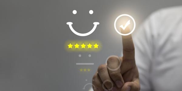 Stars and a smile symbol on a screen - with a finger pointing to a tick on the screen. Stars and a smile symbol on a screen - with a finger pointing to a tick on the screen.