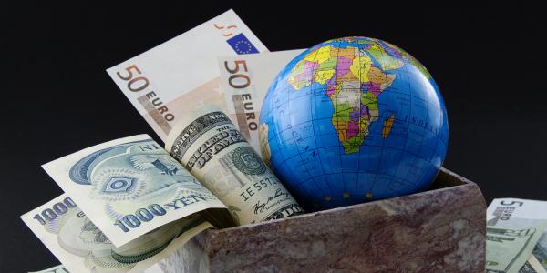 a globe of the world sat in a box with various foreign currency a globe of the world sat in a box with various foreign currency
