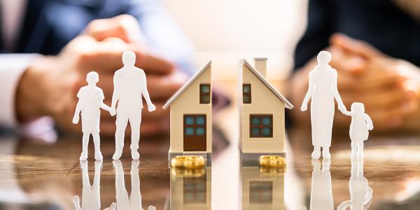 a small mode house cut in half on the left shows a dad with a child and on the right shows a mum with a different child. a small mode house cut in half on the left shows a dad with a child and on the right shows a mum with a different child.