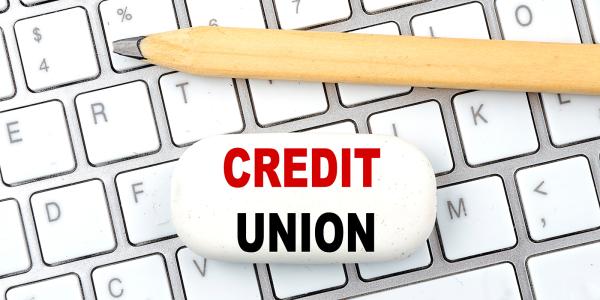 a keyboard with a pen sat on top and an eraser with the words 'CREDIT UNION' printed on it. a keyboard with a pen sat on top and an eraser with the words 'CREDIT UNION' printed on it.