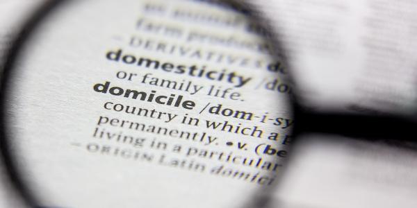 The dictionay definition of 'DOMICILE' being looked at through a magnifying glass. The dictionay definition of 'DOMICILE' being looked at through a magnifying glass.