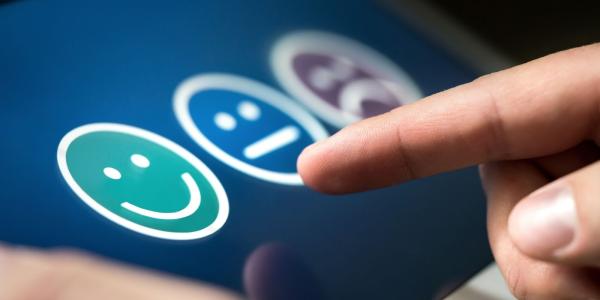 Three symbols on a screen - a smiley face, a neither happy or sad face, a sad face, and a finger pointing at the screen. Three symbols on a screen - a smiley face, a neither happy or sad face, a sad face, and a finger pointing at the screen.