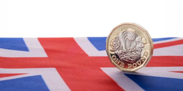 a UK flag with an English £1 coin sat on top a UK flag with an English £1 coin sat on top