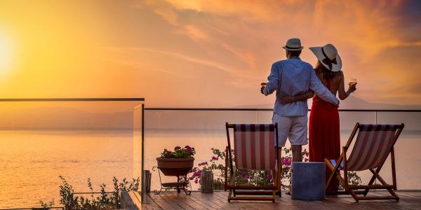 a couple looking out over a balcony at a sunset a couple looking out over a balcony at a sunset