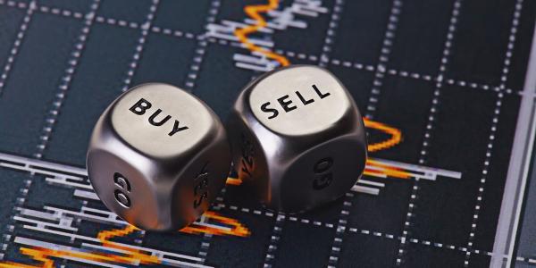 two metal dice with the words 'BUY' and 'SELL' on them, in the background a graph can be seen. two metal dice with the words 'BUY' and 'SELL' on them, in the background a graph can be seen.