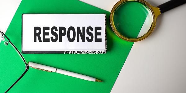a notebook with the word 'RESPONSE' typed on it, a magnifying glass, a pen and a pair of glasses a notebook with the word 'RESPONSE' typed on it, a magnifying glass, a pen and a pair of glasses
