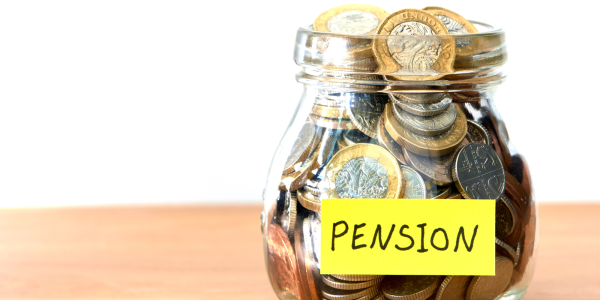 A glass jar filled with coins, a note is stuck to the jar that reads 'PENSION'. A glass jar filled with coins, a note is stuck to the jar that reads 'PENSION'.